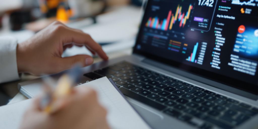 Person analyzing data on a laptop and notepad.
